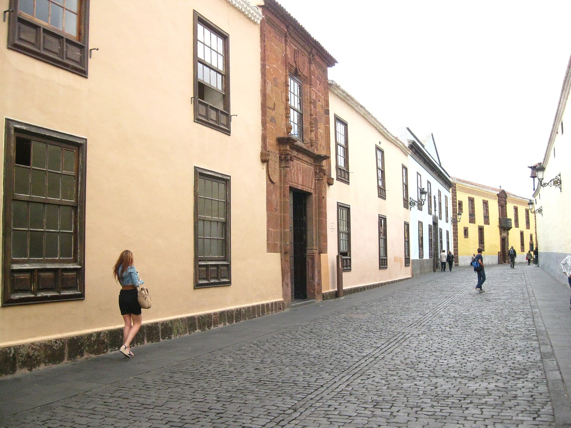 A cobbled street in the old town of San Cristobal de La Laguna, Tenerife, with rendered colonial houses and the carved stone portal of the Casa del Corregidor