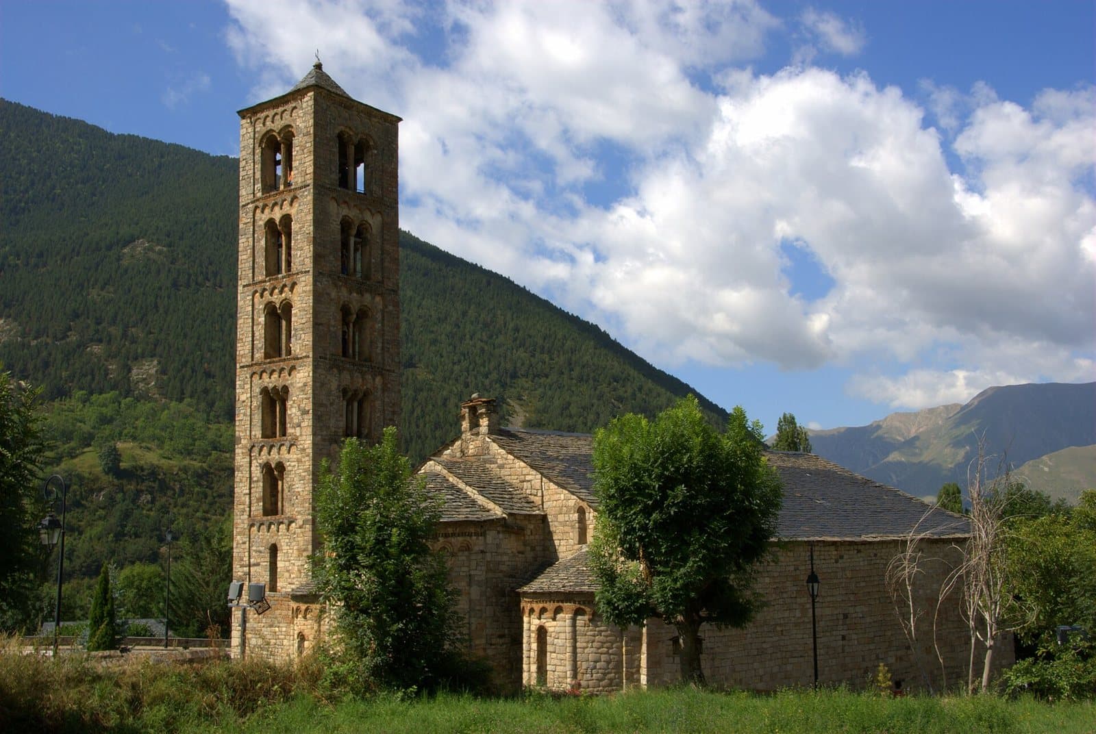 The twelfth-century church of Sant Climent de Taüll in the Vall de Boí, its six-storey Lombard bell tower rising in front of a wooded Pyrenean slope