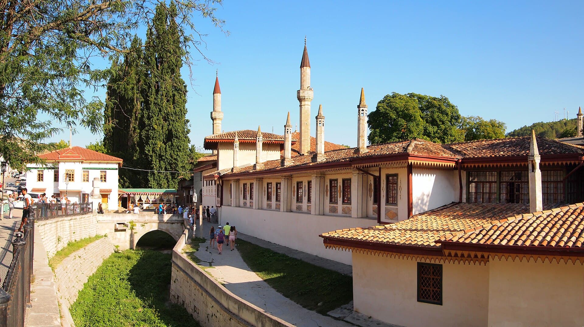 The Khan's Palace at Bakhchysarai from above the stone-lined Churuk-Su channel, its tiled roofs and painted window frames below the minarets of the Great Khan Mosque
