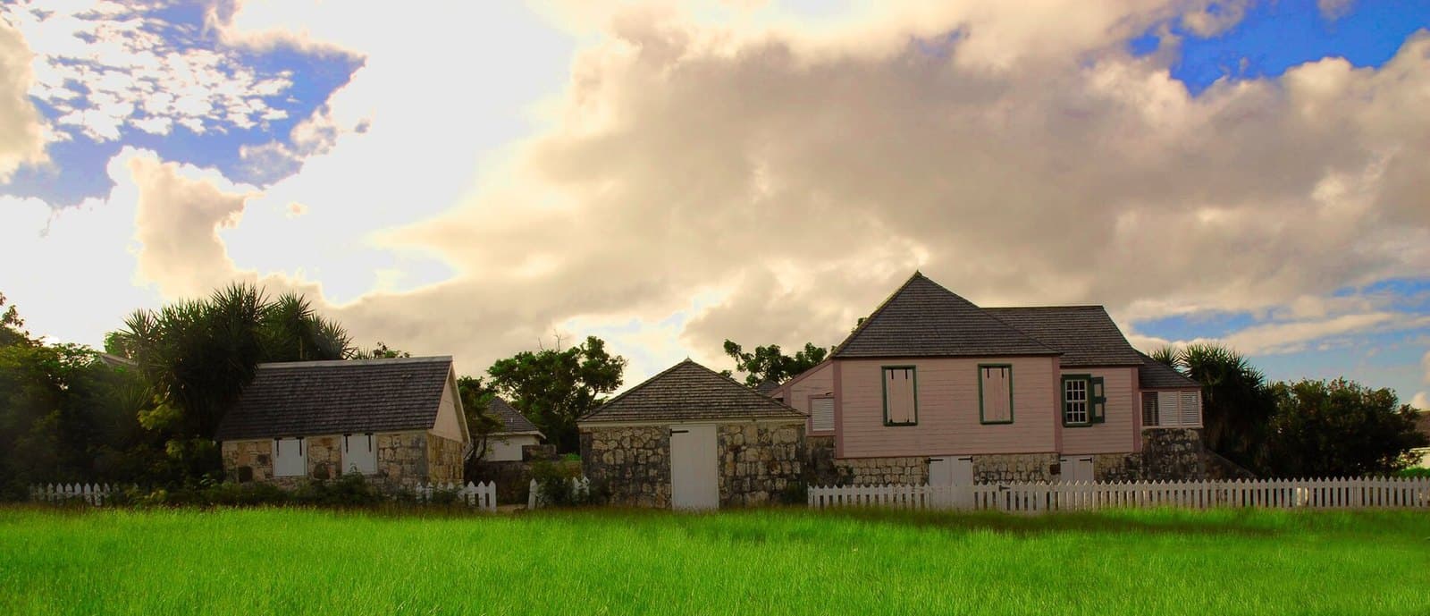 Wallblake House in The Valley, Anguilla: a pink timber house on a coral-stone base, with stone outbuildings behind a white picket fence