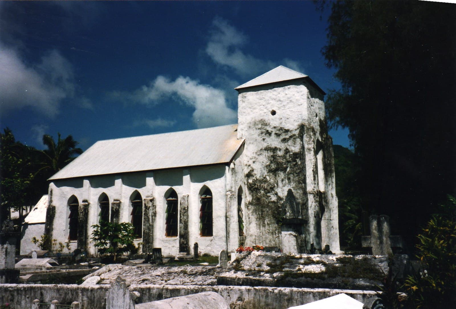 The whitewashed Cook Islands Christian Church at Avarua on Rarotonga, built of coral limestone in 1853, with family tombs in the graveyard around it