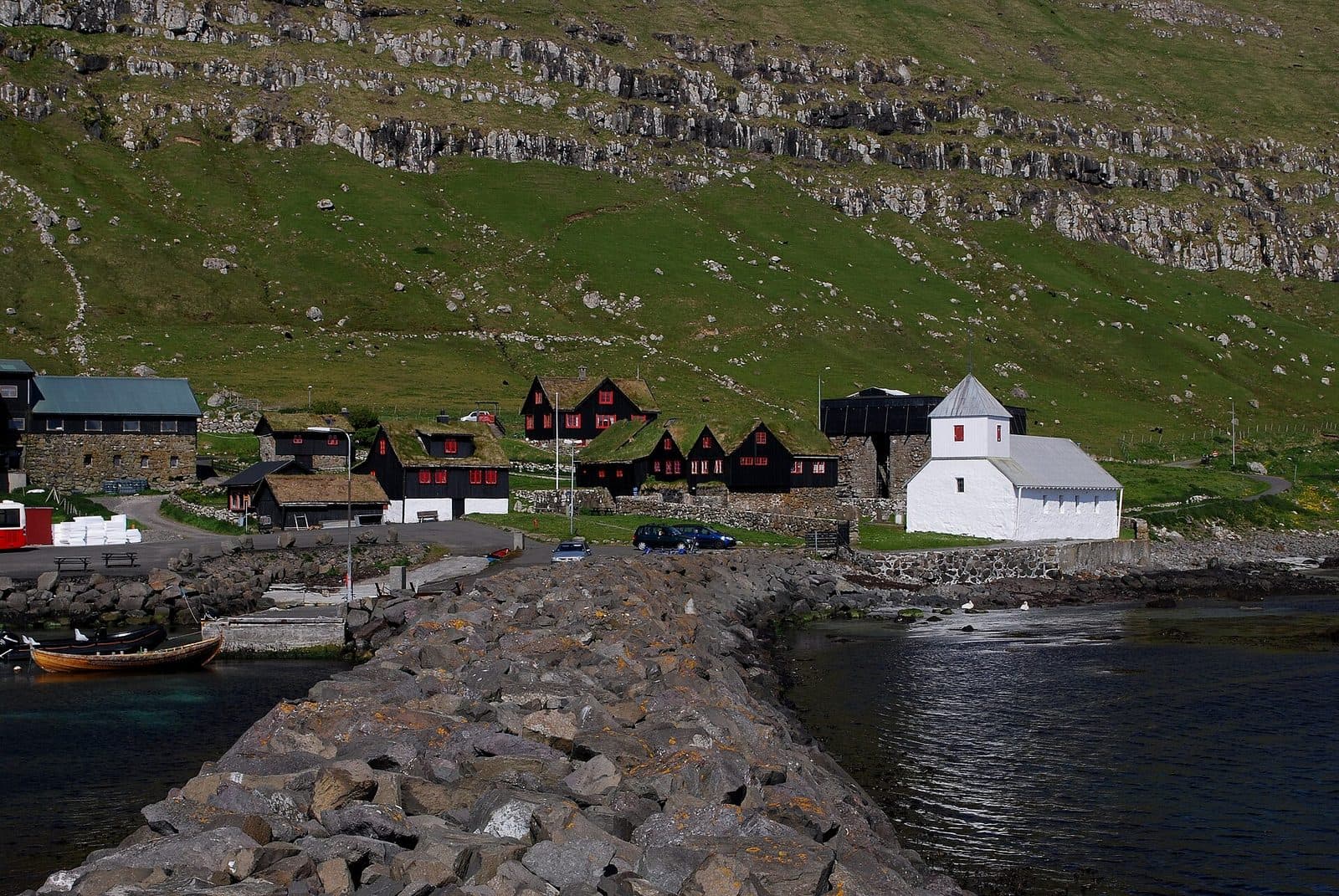 The village of Kirkjubøur on Streymoy, with the whitewashed medieval St Olav's Church and the black turf-roofed farm buildings below a grass slope