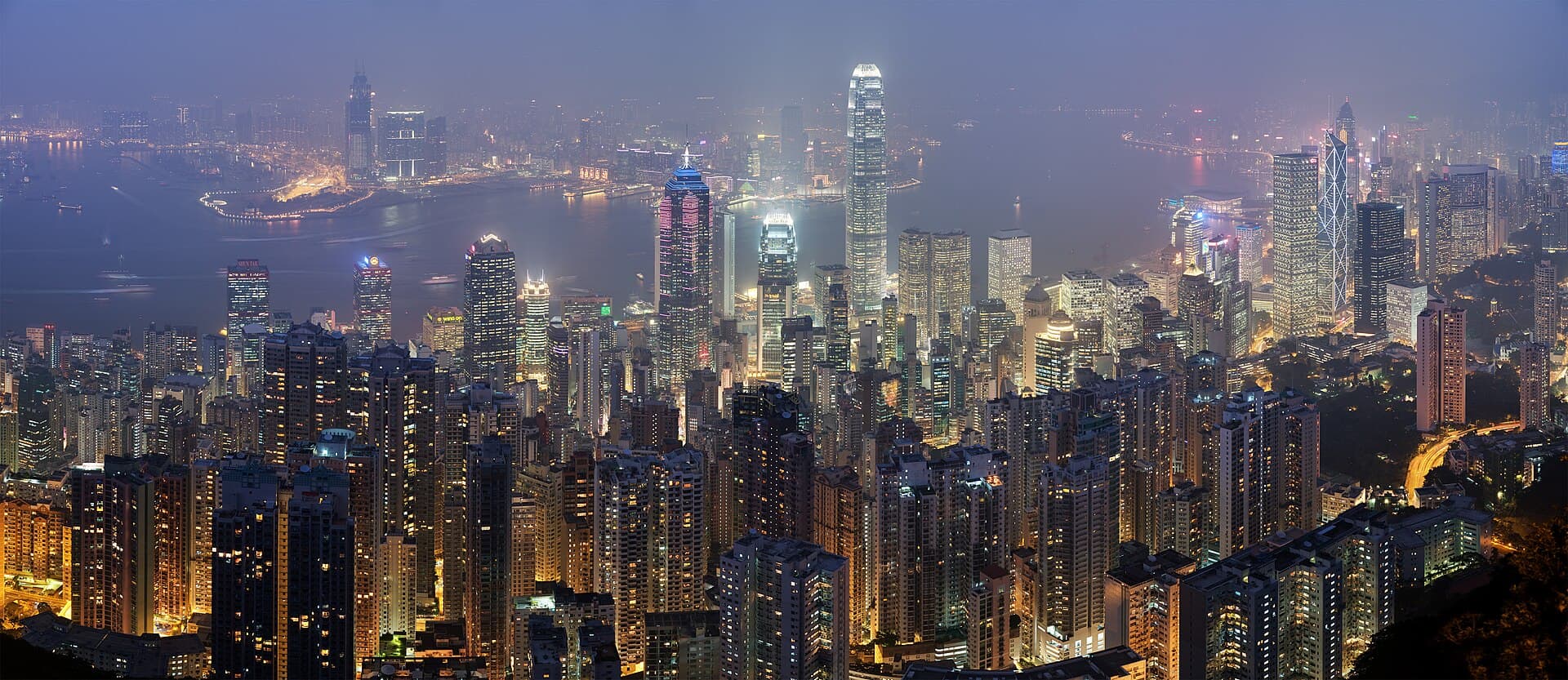 The Hong Kong skyline and Victoria Harbour at dusk, photographed from a path on Victoria Peak