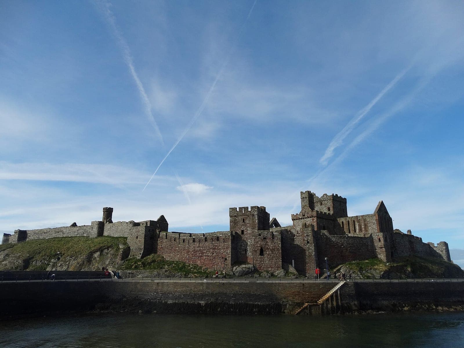 Peel Castle on St Patrick's Isle, its red sandstone curtain walls and towers seen from the breakwater at Peel, Isle of Man