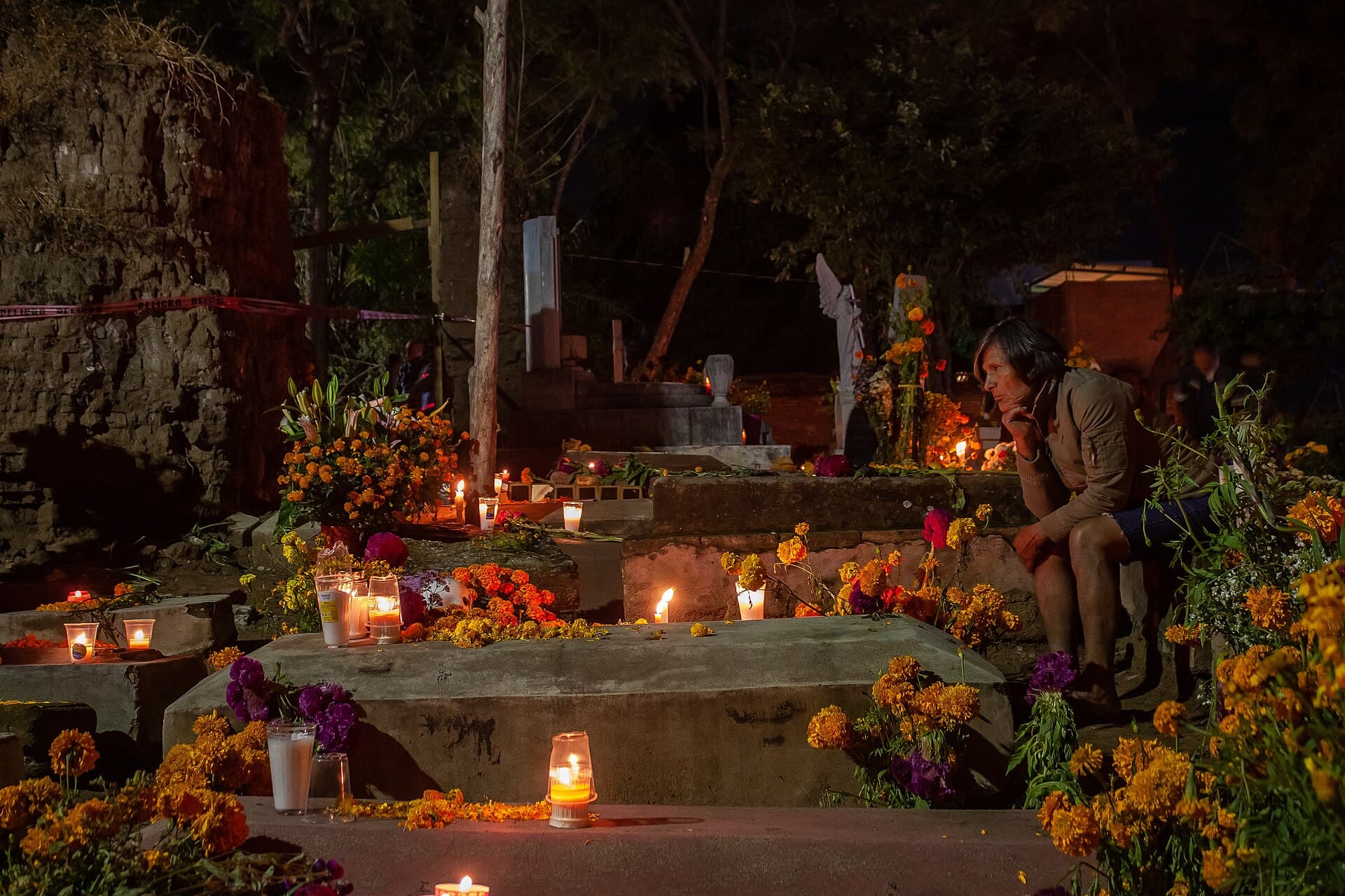 Families keeping vigil among candlelit and flower-covered graves in the cemetery at Santa Cruz Xoxocotlan, Oaxaca, during the night of the Day of the Dead