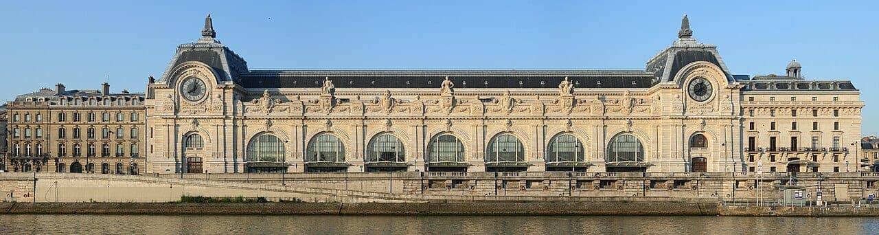 The Musee d'Orsay seen from across the Seine, its Beaux-Arts stone facade and the twin station clocks of the former Gare d'Orsay